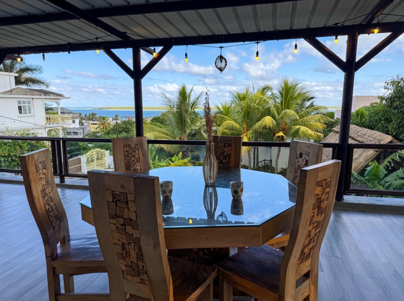 Covered terrace with octagonal dining table, fairy lights and ocean view to Le Morne