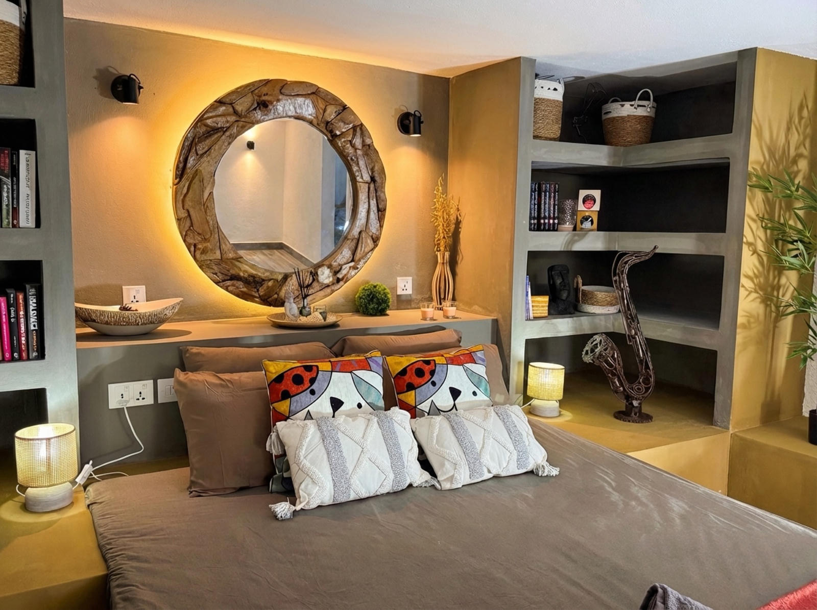 Bedroom with illuminated round wooden mirror and decorative shelves