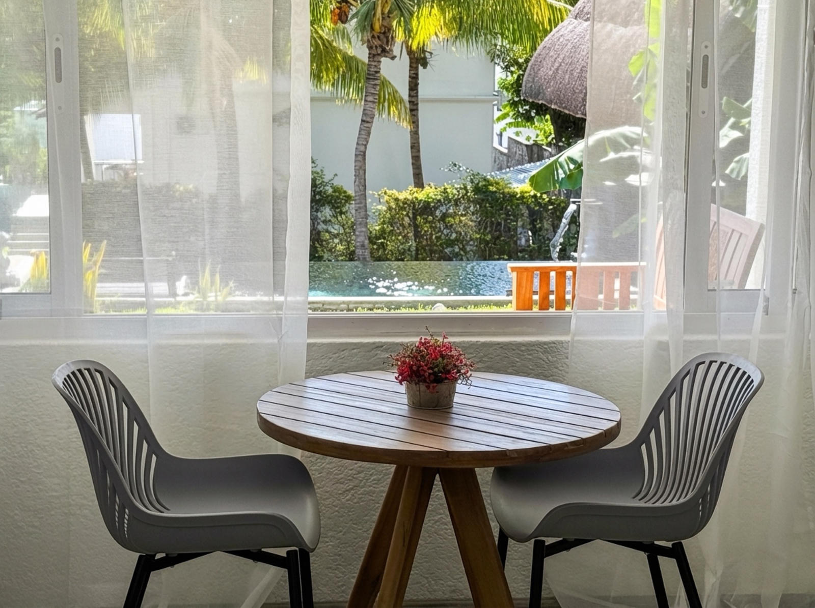 Dining table for two with view of the pool and tropical garden